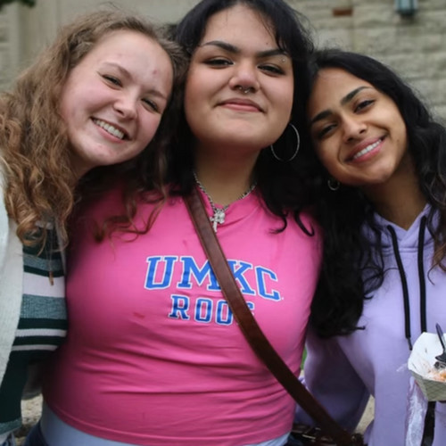 Three smiling young women standing closely together
